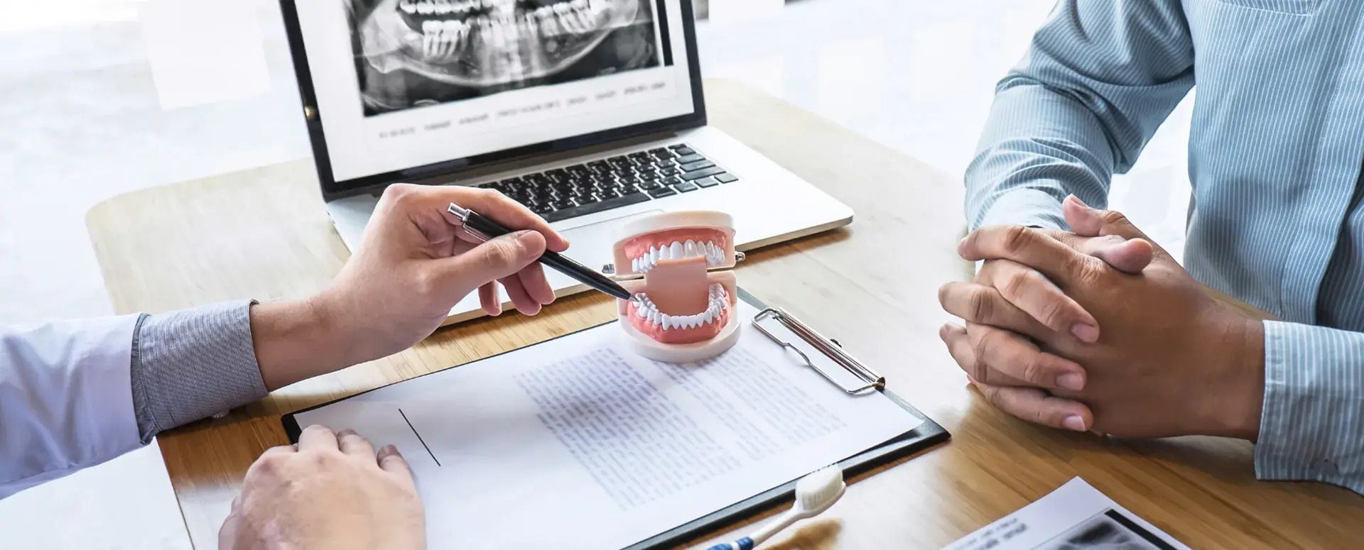 Dentist explaining treatment with a dental model and panoramic X-ray