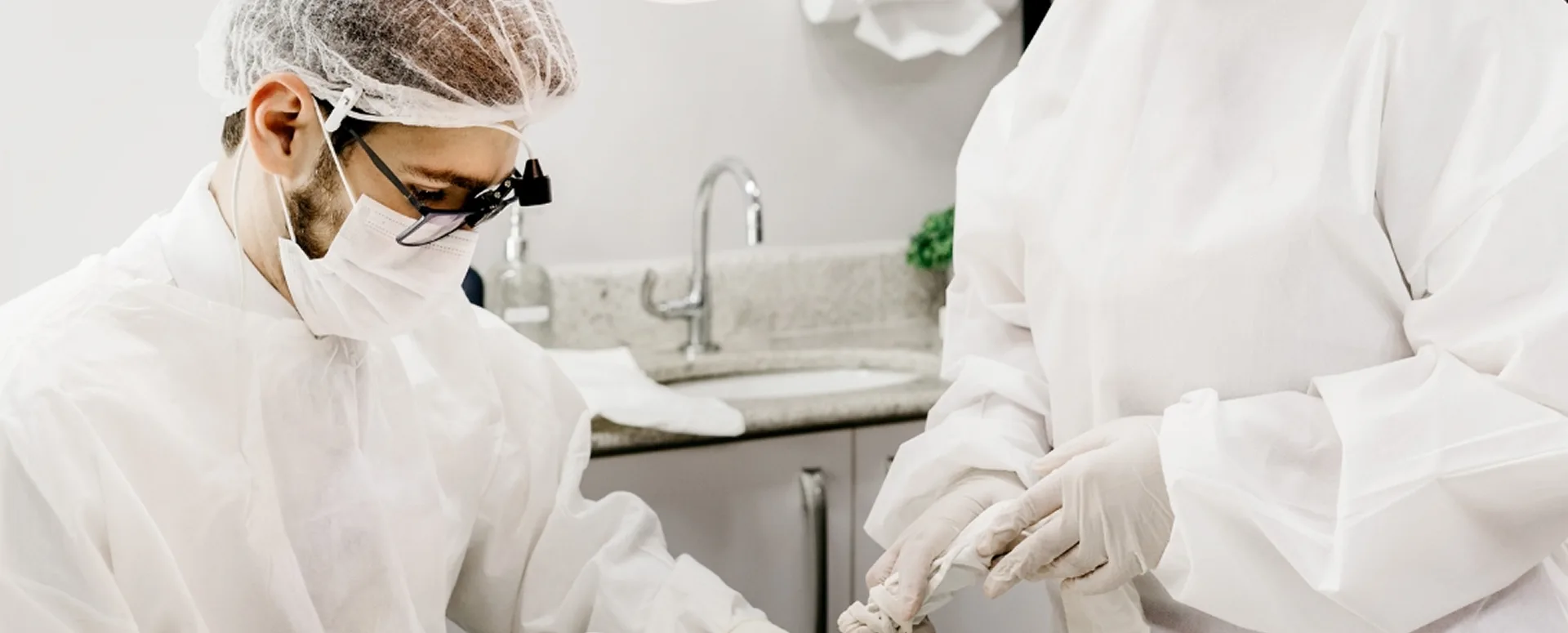 Dental clinicians wearing protective clothing and magnifying loupes during a procedure